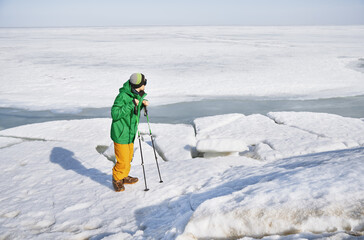 Fototapeta na wymiar Young adult man with walking sticks outdoors exploring icy landscape