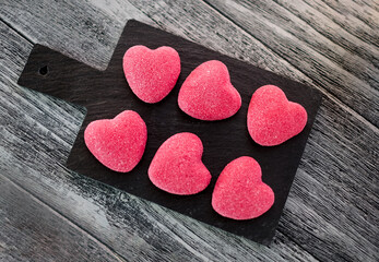 Fototapeta na wymiar Valentine's Day dessert. Sweet hearts shaped set on stone cutting board on wooden background. Top view, close-up, selective focus