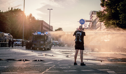 Police water cannon in sunset light during G20 summit protests in Hamburg, Germany