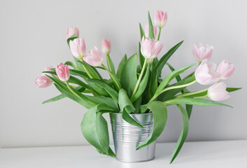 Naklejka na ściany i meble Spring white tulips in an abstract vase on the shelf, interior room