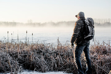 Samotny mężczyzna na brzegu jeziora zimą - obrazy, fototapety, plakaty