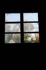 window in abandoned building in the dark with autumn landscape outside