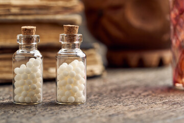 Two bottles of homeopathic remedies, with vintage books in the background