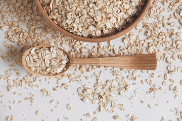 Oatmeal in a wooden plate and spoon on a white background. Top view. Copy, empty space for text