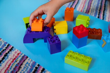 Chils playing with construction toy blocks building a tower in a sunny kindergarten room. Kids playing. creative games, boy building with blocks. development of thinking and imagination