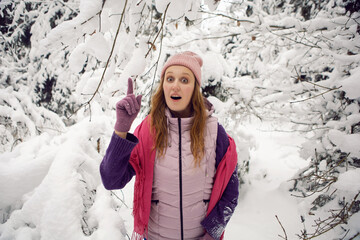 winter emotional woman in pink hat having fun in the forest with snow