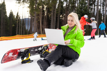 woman snowboarder working laptop in winter mountains