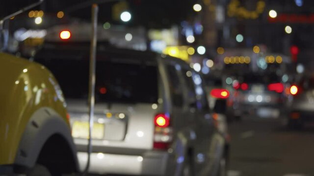 New York City heavy street traffic by night, queue of blurry slow driving cars