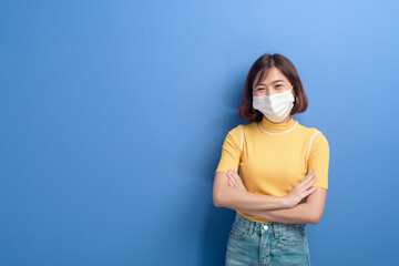 Portrait of young beautiful asian woman wearing a surgical mask over studio background, covid19...