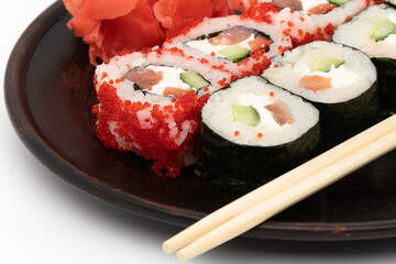 Different types of sushi on a black plate, white background. Isolate