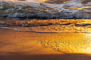 Spiegelung des Sonnenuntergangs am Strand im Sand