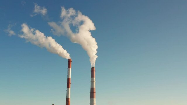 Industrial air pollution. Exhaust gases are carried into the sky. Smoke from industrial chimneys on a background of blue sky. Smoke from factory chimneys in an urban environment. Concept: environmenta