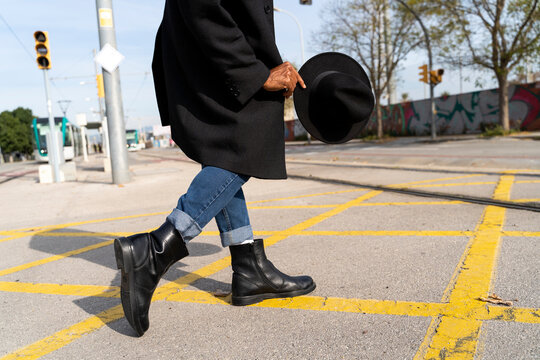 Fashionable man holding hat while walking on street