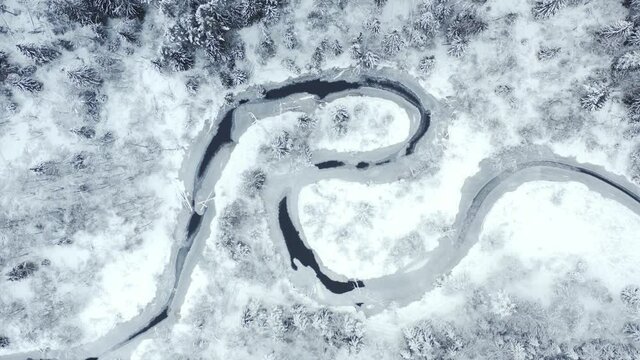 Top view s-curved frozen winding river in winter snowy forest