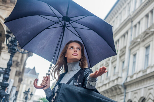 Businesswoman looking away under umbrella during rainy season in city