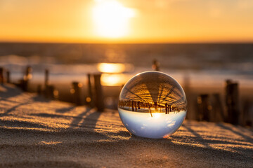 Glaskugel im Sand am Strand im Sonnenuntergang