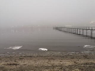 Pier in the fog on the banks of the winter river