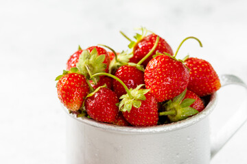 Strawberries in a metal mug on a light gray background