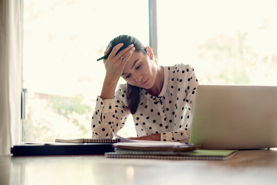Tired businesswoman sitting with head in hands while working at office