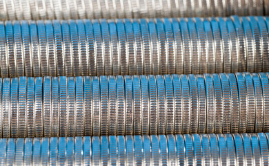 many round metal coins of silver color illuminated in blue