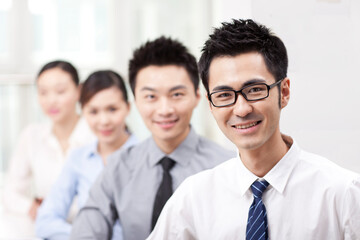 Executives sitting at conference table focus on woman in foreground 