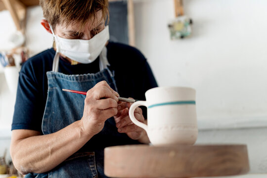 Female artist painting cup in ceramic workshop