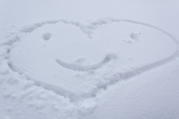 Fototapeta na wymiar Smiling happy heart symbol on white snow surface wintery day valentines day love and romance card 