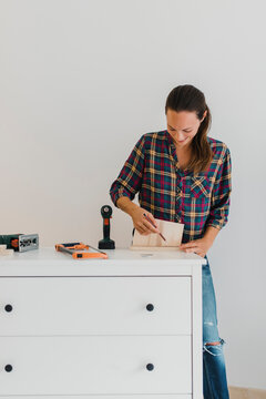 Mid adult woman  marking on wood while doing DIY work at home