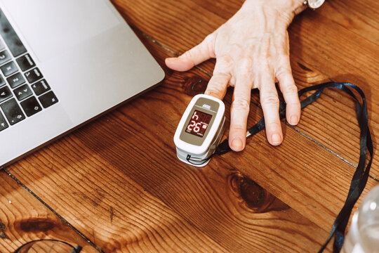 Senior woman checking pulse with oximeter at home