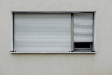 Bright stone wall with two window and aluminum shutter, jalousie rolled up symbol for lockdown, no person