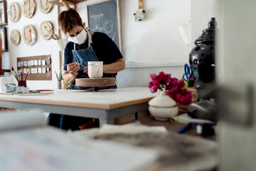 Small business owner painting cup in her crafts workshop