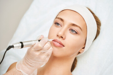 Permanent makeup. Beauty spa procedure. young woman. Face tattoo. Lip micropigmentation....