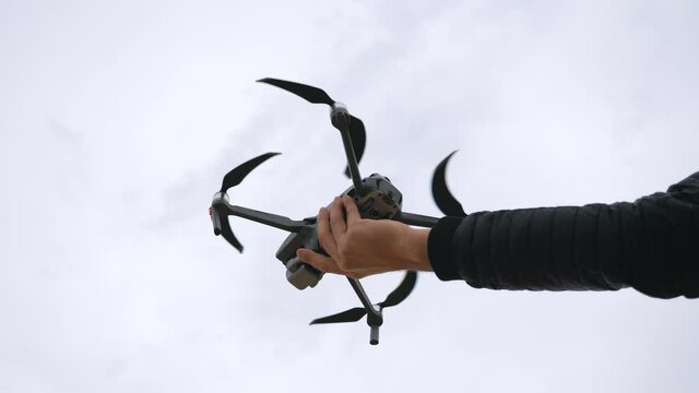 Low view to quadcopter tacking off from male hand. Drone operator tacking aerial pictures or filming video of scenic environment. Modern technology concept. Slow motion