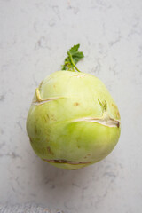 Green kohlrabi on a marble kitchen counter, top view.