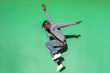 Young african man jumping up isolated on green colored background.