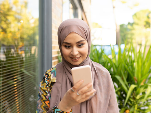 Smiling woman using mobile phone while standing outdoors