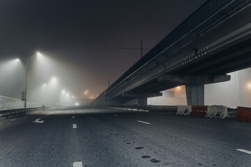 Foggy misty night road illuminated by street lights