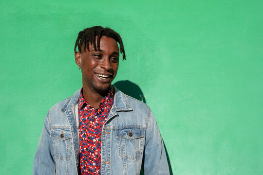 Portrait of young african man smiling and looking sideways on green colored  background. Stock Photo | Adobe Stock