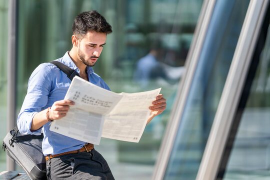 Young businessman reading newspaper while sitting outdoors