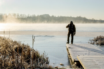 Samotny mężczyzna na ośnieżonym pomoście na brzegu jeziora