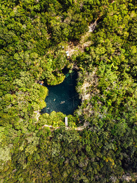 Aerial view of cenote surrounded by green lush jungle