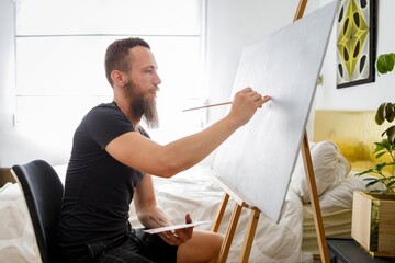 Male artist painting on canvas at home