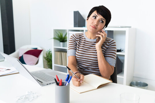 Portrait of businesswoman talking on smart phone at office desk