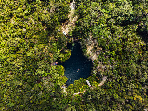 Aerial view of cenote surrounded by green lush jungle