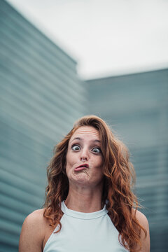 Young woman showing weird facial expression while standing outdoors
