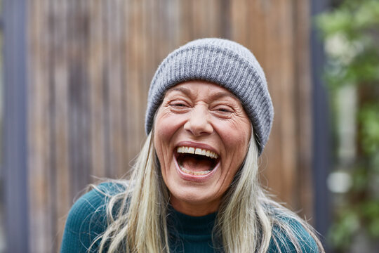 Laughing mature woman against house