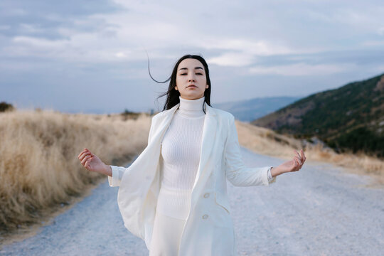 Young woman wearing white jacket standing on road
