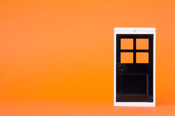 closed toy black door isolated on orange background