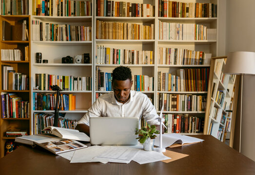 Male environmentalist using laptop while working on wind turbine project at home office