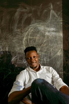 Smiling male entrepreneur sitting against scribble wall